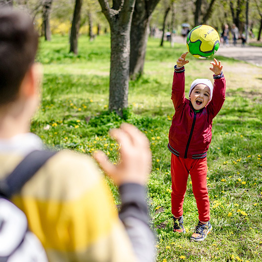 Erwachsener und Kind spielen mit einem Ball