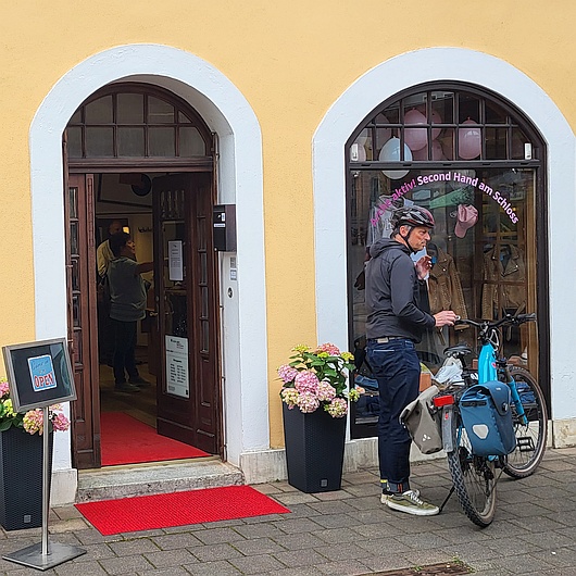 Ein Mann parkt sein Fahrrad vor dem Secon-Hand-Laden am Schloss in Ansbach