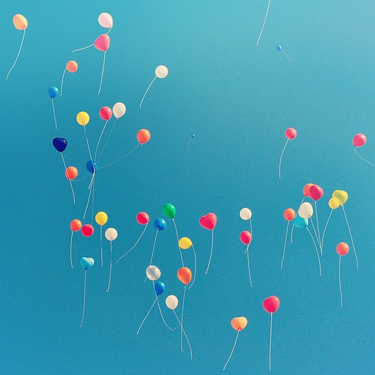 Ein blauer Sommerhimmel mit bunten Luftballons (Foto: Al Soot // unsplash)